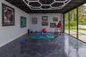 Polished concrete flooring, geometric LED ceiling lighting, and expansive sliding glass doors opening to a paved patio area