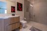 Modern bathroom featuring a wood-finish vanity with a white countertop, walk-in shower with floor-to-ceiling tile, frameless glass enclosure, and a wa