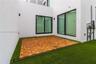 Modern outdoor patio featuring modular wood-finish decking, synthetic turf, minimalist white stucco exterior walls, and floor-to-ceiling sliding glass