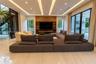 Living area featuring a coffered ceiling with integrated cove lighting, recessed lighting, polished stone flooring, a full-height wood-paneled media w