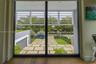 Floor-to-ceiling glass paneling featuring adjustable white horizontal louvers, wood-finish flooring, and exterior hardscaping with concrete pavers and