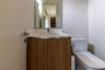 Vanity featuring a wood-finish cabinet, white countertop with an integrated basin, wall-mounted mirror, and chrome faucet