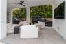 Covered outdoor space featuring large-format tile flooring, recessed lighting, a matte black ceiling fan, and wall-mounted television interface