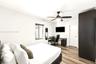 Interior room featuring wood-finish flooring, a ceiling fan with integrated lighting, and a built-in dark cabinetry unit