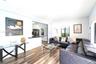 Open-concept interior featuring wood-finish flooring, recessed lighting, and a kitchen pass-through with a dark solid-surface countertop