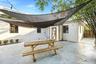 Outdoor patio featuring a concrete surface, overhead tension shade sails, exterior string lighting, and wood privacy fencing