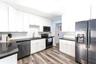 Kitchen featuring white cabinetry, dark stone-finish countertops, textured tile backsplash, stainless steel appliances, and wood-finish flooring