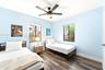 Interior room featuring wood-finish flooring, two dual-pane windows, and a matte black ceiling fan