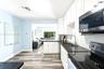 Kitchen featuring white shaker-style cabinetry, dark stone countertops, stainless steel appliances, a textured tile backsplash, and wood-finish floori