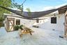 Concrete patio featuring a suspended shade sail, string lighting, and wood-trim exterior storage access