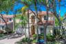 Two-story residence featuring a stucco facade, red tile roof, arched entryway, second-story balcony with decorative railing, and a brick-paver drivewa
