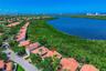 Aerial perspective featuring terracotta-style roofing, two-story structural design, and proximity to coastal water and native vegetation