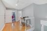 Interior hallway featuring wood-finish flooring, white paneled doors, recessed lighting, and a white vertical balustrade