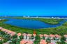 Aerial perspective of a multi-story residence with a tiled roof, situated within a coastal community featuring proximity to a large water basin and de