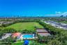 Expansive outdoor recreational complex featuring two fenced tennis courts, a swimming pool with paved deck, and a clubhouse with a clay-tile roof