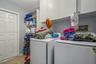 Laundry room featuring white wall-mounted cabinetry, open shelving, and tile flooring