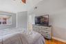 Vaulted ceiling with a ceiling fan, neutral wall paint, wood-finish flooring, and single-hung window with a view of exterior tile roofing