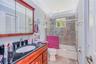 Bathroom featuring a wood-finish vanity with a dark polished countertop, undermount sink, multi-panel medicine cabinet, and a bathtub enclosure with s