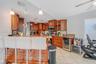 Kitchen featuring wood cabinetry, stone countertops, breakfast bar, and under-counter beverage refrigerator