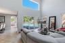 Double-height ceiling with clerestory windows, tile flooring, and oversized sliding glass doors opening to a screened pool enclosure