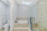 Skylit bathroom featuring a tiled platform soaking tub, separate glass-enclosed shower, stone-finish surround, and a porcelain toilet