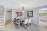 Dining space featuring neutral tile flooring, arched entryways, a central metal pendant light fixture, and stairs with wood treads