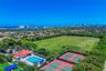 Aerial perspective featuring a clubhouse, an outdoor swimming pool with a surrounding paved deck, and two hard-surface tennis courts