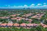 Aerial perspective of a residential community featuring tile-roofed structures, dense tree canopies, and a distant city skyline