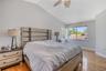 Vaulted ceiling with a central fan, light-toned wood-finish flooring, and large sliding windows
