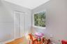 Bedroom featuring wood-finish flooring, a double-panel louvered closet, and a large horizontal window providing exterior greenery