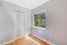 Neutral wall finishes, wood-finish flooring, and white louvered-style closet doors, featuring a sliding window with outdoor greenery