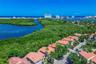 Aerial perspective of a coastal residential community featuring tile roofs, lush natural vegetation, expansive waterways, and a clear horizon line