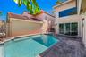 Stucco exterior with a tiled roof featuring an in-ground swimming pool and expansive paver patio