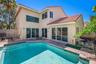 Two-story stucco exterior featuring a clay tile roof, a swimming pool with integrated stairs, and multi-panel sliding glass doors