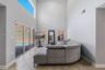 Double-height ceilings, ceramic tile flooring, expansive sliding glass doors, transom window, and dual vertical windows
