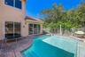 Backyard featuring an in-ground pool with built-in stairs, paver stone decking, and white metal fencing