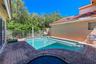 In-ground pool with built-in stairs, enclosed by metal perimeter fencing, featuring paver hardscaping and a clay tile roof