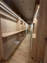 Custom Men’s Primary closet w storage system featuring light wood-finish cabinetry, integrated linear LED shelving illumination, open-concept shelving