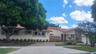 Exterior featuring a stucco facade with stone masonry accents, a tiled roof, a multi-car garage, and a concrete driveway