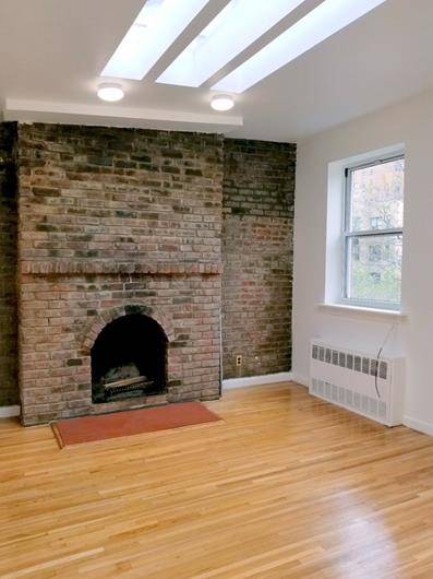 Spacious apartment with an abundance of charming features including a decorative fireplace and exposed brick.