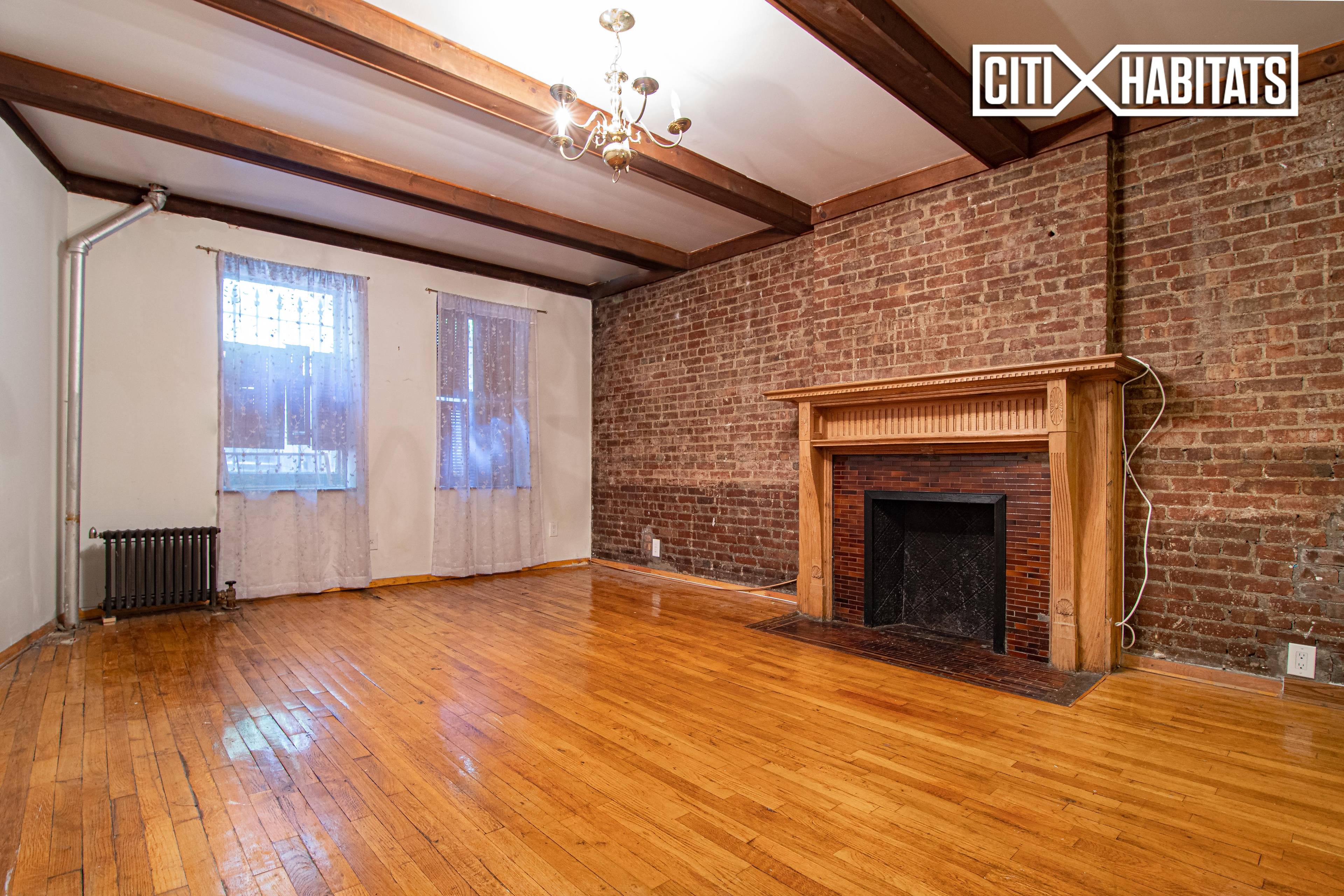 This large studio has walls of exposed brick, a decorative fireplace, a beamed ceiling, stainless steel appliances, and good closet space.