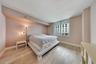 Primary bedroom with blonde hardwood floors, large city-view window, and warm ambient lighting at One Miami East Residence 3110 — Downtown Miami luxury condo