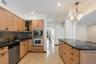 Kitchen featuring wood-finish cabinetry, granite countertops, tile backsplash, and integrated stainless steel appliances including a wall oven and mic