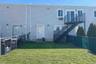 Expansive green lawn with chain-link fencing, a multi-level exterior staircase, and multiple entry points