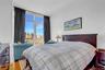 Bedroom with floor to ceiling windows, a view of city, and wood finished floors