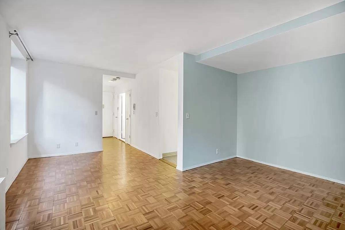 This alcove studio apartment features beautiful hardwood floors, a flexible living layout, providing ample space for a home office, couch, coffee table, and TV.