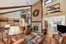 Living room featuring a chandelier, high vaulted ceiling, beam ceiling, hardwood / wood-style flooring, and a fireplace