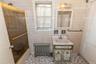 Full bath with radiator, shower / bath combination with glass door, tile walls, and vanity