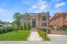 View of front of house with french doors, a high end roof, brick siding, concrete driveway, and a chimney