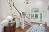 Hardwood flooring, grand staircase with white risers and wood treads, chandelier, double French doors, transom window with arched top